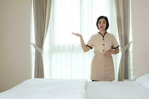 giovane cameriera asiatica nella camera d'albergo che guarda l'obbiettivo foto