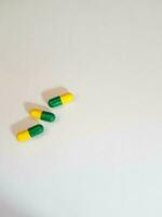 isolato bianca foto di tre medicina capsule verde e giallo.