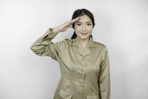 un' giovane asiatico governo lavoratore indossare un' Marrone uniforme fare saluto posa, isolato di bianca sfondo foto