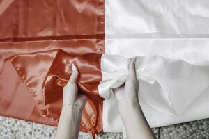 mani mettere insieme Tenere indonesiano rosso e bianca bandiera. dell'Indonesia indipendenza giorno concetto foto