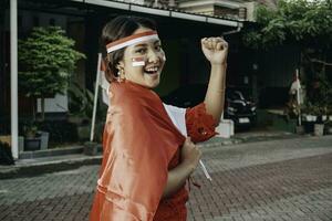 contento sorridente indonesiano donna indossare rosso kebaya Tenere dell'Indonesia bandiera per celebrare Indonesia indipendenza giorno. all'aperto servizio fotografico concetto foto