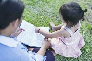 ragazza con libro su sua testa all'aperto femmina alunno ritratto, formazione scolastica concetto contento carino ragazzo sorridente con apprendimento. foto