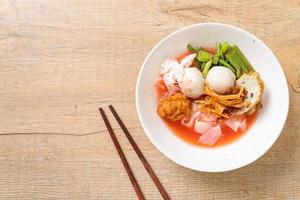 noodle in stile thai con tofu assortito e polpette di pesce in zuppa rossa foto