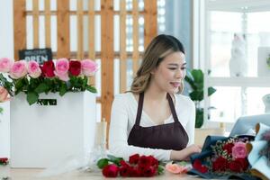 bellissimo asiatico donna fioraio Lavorando nel fiore negozio. foto