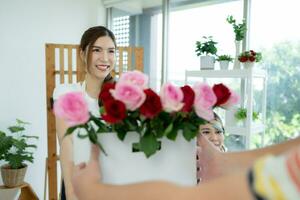 giovane asiatico donna fioraio Lavorando a fiore negozio, lei è contento e sorridente. consegnare fiori per i clienti foto