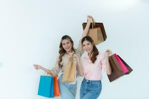 Due contento asiatico donne Tenere shopping borse isolato su bianca sfondo. foto