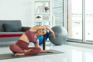 asiatico giovane salutare donna nel articoli sportivi praticante yoga a casa, sport ragazza Meditare nel vivente camera a casa foto