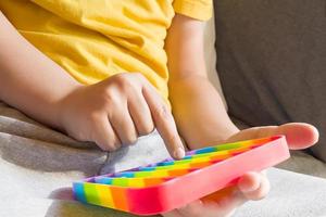 colorato antistress sensoriale fidget push pop it giocattolo nelle mani dei bambini foto