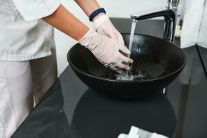 avvicinamento. medico lavaggio mani nel clinica lavabo a partire dal elegante nero marmo nel contemporaneo terme clinica con bellissimo design foto