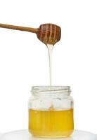 gocciolante miele a partire dal miele mestolo in vaso di biologico salutare dolce naturale Miele, isolato al di sopra di bianca sfondo con copia spazio foto