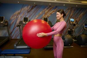 bellissimo mezzo anziano donna con atletico salutare corpo, opera su con un' fitness palla nel il palestra. salutare stile di vita, sport, fitness. foto