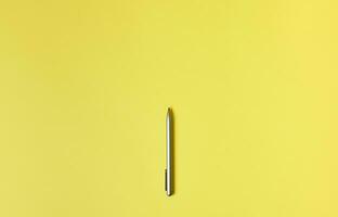 piatto posizione. superiore Visualizza di un' grigio penna isolato su un' giallo sfondo. civettuolo spazio foto