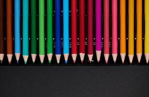 piatto posare di multicolore di legno matite per disegno su un' nero superficie foto