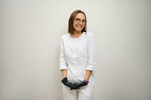 messa a fuoco su facciale espressioni di un' bellissimo femmina medico stagista, medico, Salute cura lavoratore nel bianca medico uniforme, sorridente trentadue denti Sorridi in posa contro bianca parete sfondo con copia spazio foto