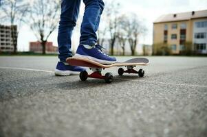 avvicinamento di skateboarder gambe. ragazzo equitazione skateboard all'aperto. concetto di tempo libero attività, sport, estremo, passatempo. foto
