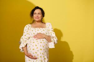 incinta donna Tenere gonfiarsi, isolato giallo studio sfondo foto
