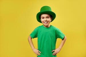 contento ridendo ragazzo indossare fata verde cappello pose per il telecamera su un' giallo sfondo. santo Patrick giorno. copia spazio foto