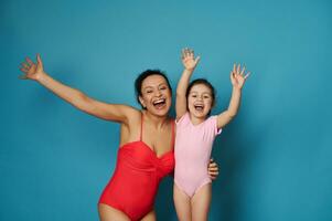 adorabile donna nel costume da bagno abbracciare carino poco ragazza e esprimendo felicità di raccolta mani foto