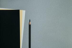 Nero, giallo e bianca lenzuola di carta e un' nero matita su un' grigio sfondo. piatto posizione, copia spazio, superiore Visualizza foto