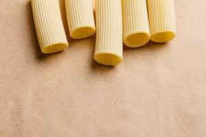 superiore Visualizza di uno genere di pasta su un' mestiere carta superficie con copia spazio. crudo tortiglioni e cannelloni foto