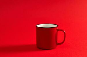 avvicinamento Immagine di uno rosso boccale su rosso sfondo con morbido ombra e copia spazio per promozione. rosso tazza. foto