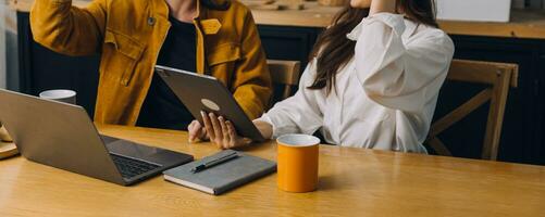 femmina studenti Nota a partire dal il libri a il asiatico ragazza biblioteca seduta a divano utilizzando il computer portatile computer e tavoletta per ricerca un in linea informazioni. nel vivente camera foto