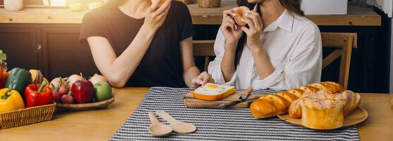 contento Due giovane donne guardare il computer portatile computer durante cucinando insieme nel cucina camera a casa. Due giovane diverso lesbica donne la spesa tempo insieme. lgbt e Genere identità concetto foto