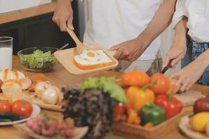 bello uomo seduta vicino il suo moglie a cucina. famiglia coppia vedere sociale media, Surf il ragnatela mentre seduta a cucina tavolo con generico il computer portatile. coppia Lavorando con il computer portatile a casa foto