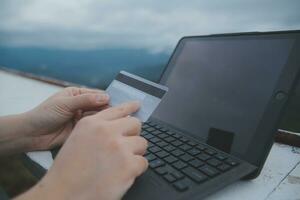 in linea pagamento, giovane donna Tenere credito carta e digitando su il computer portatile foto