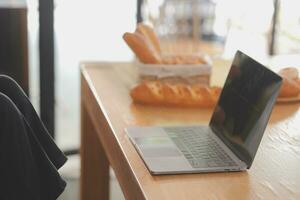 ritratto di bella libero professionista femmina Lavorando digitando su il computer portatile computer seduta a tavolo sorridente guardare per schermo nel cucina. attraente testa Rossa giovane donna a distanza Lavorando su il computer portatile a partire dal casa ufficio. foto