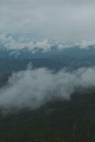 bellissimo panoramico Visualizza di nebbia e nuvole nel lontano strati montagne gamma con blu cielo nel mattina foto