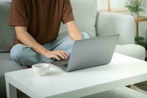 uomo opera a partire dal casa. opera in linea su il computer portatile. asiatico uomo d'affari Lavorando in linea attività commerciale concetto con sociale distanziamento il computer portatile in linea incontro. foto