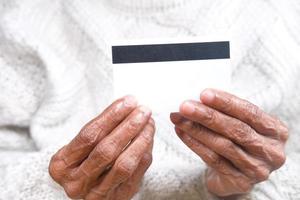 primo piano di una donna anziana che tiene in mano una carta di credito