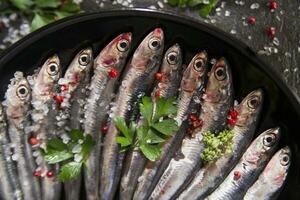 fresco sardine nel un' nero piatto con erbe aromatiche foto