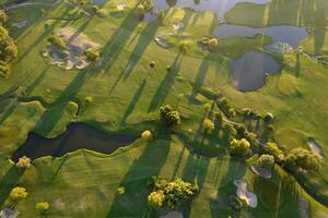 aereo Visualizza di un' verde golf corso a tramonto foto