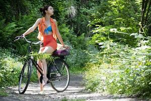 ragazza vestito nel arancia Ciclismo nel il boschi foto