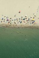 un' spiaggia con molti persone su esso foto