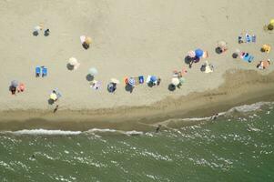 un' spiaggia con molti persone su esso foto