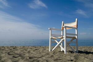 un' spiaggia sedia su il sabbia con un' blu cielo foto