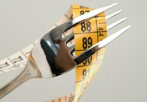 un' forchetta e coltello circondato di misurazione nastro foto