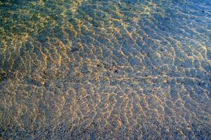 il acqua è chiaro e blu con sabbia foto