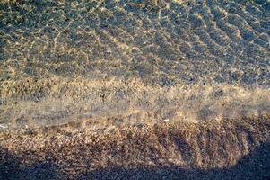 il acqua è chiaro e blu con sabbia foto