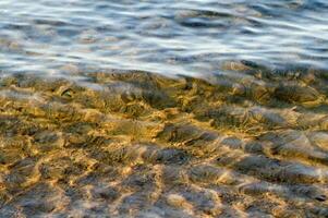 il acqua è chiaro e blu con sabbia foto