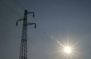 un' silhouette di un elettricità Torre con il sole dietro a esso foto