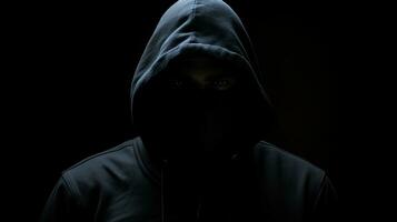 silenzioso figura nel cappuccio su buio fondale nascosto viso simboleggiante delinquenza mistero segretezza e anonimato foto