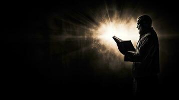 un' uomo detiene un' Bibbia prega nel nero e bianca con un' leggero bagliore foto