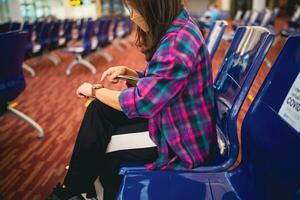 donna in attesa per partenza a il aeroporto su il tuo vacanza hold passaporto e smartphone mentre in attesa imbarco su partenza la zona internazionale aeroporto foto