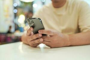 rilassato giovane asiatico uomo utilizzando inteligente Telefono la spesa tempo controllo notizia sociale media. foto