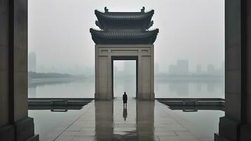 un' uomo in piedi su un' grande Cinese architettura cancello nebbioso nebbioso, lago e città a il sfondo. ai generato foto