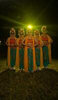 un' gruppo di indonesiano tradizionale ballerini danza con loro amici nel davanti di il palcoscenico luci foto